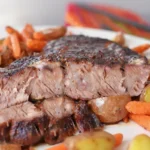Air fryer chuck roast with crispy exterior, sliced and served with roasted potatoes and carrots